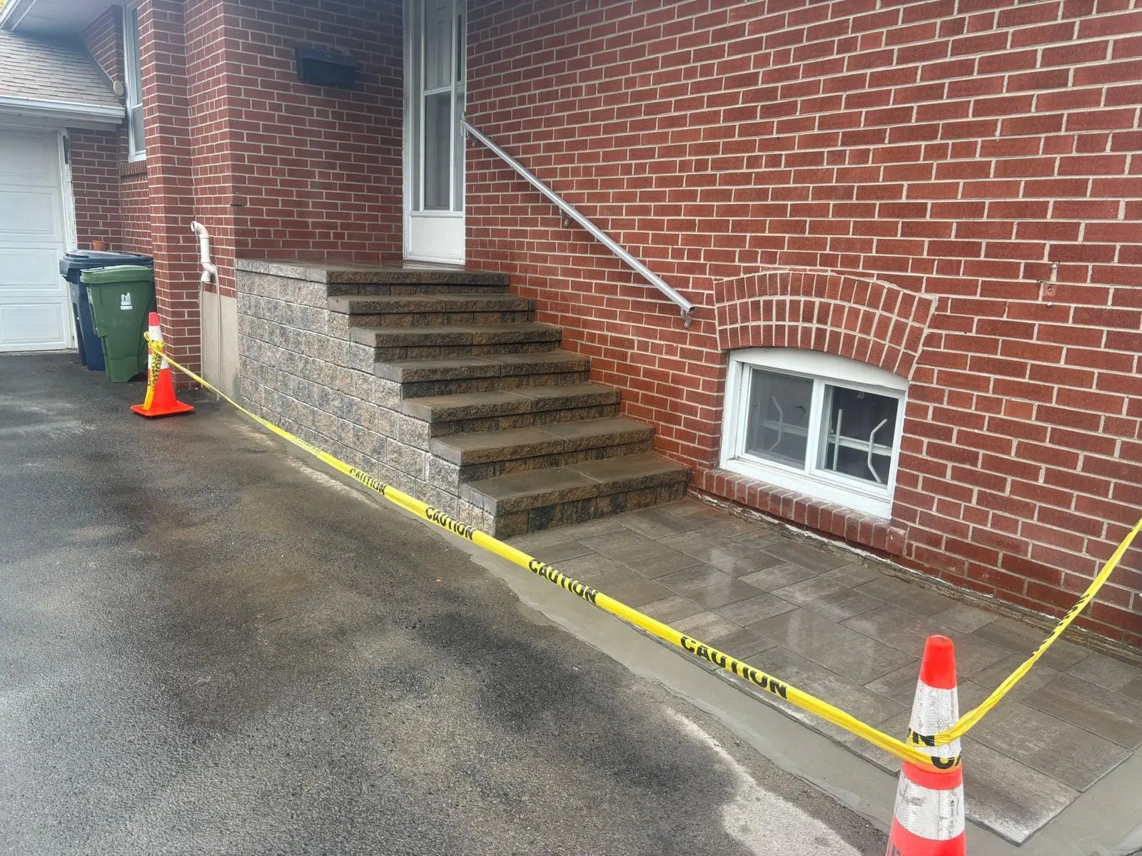 Finished masonry stairs and paver landing beside a red brick house