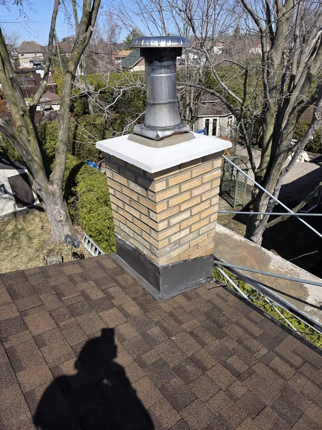 Rebuilt brick chimney with white concrete cap and metal flue