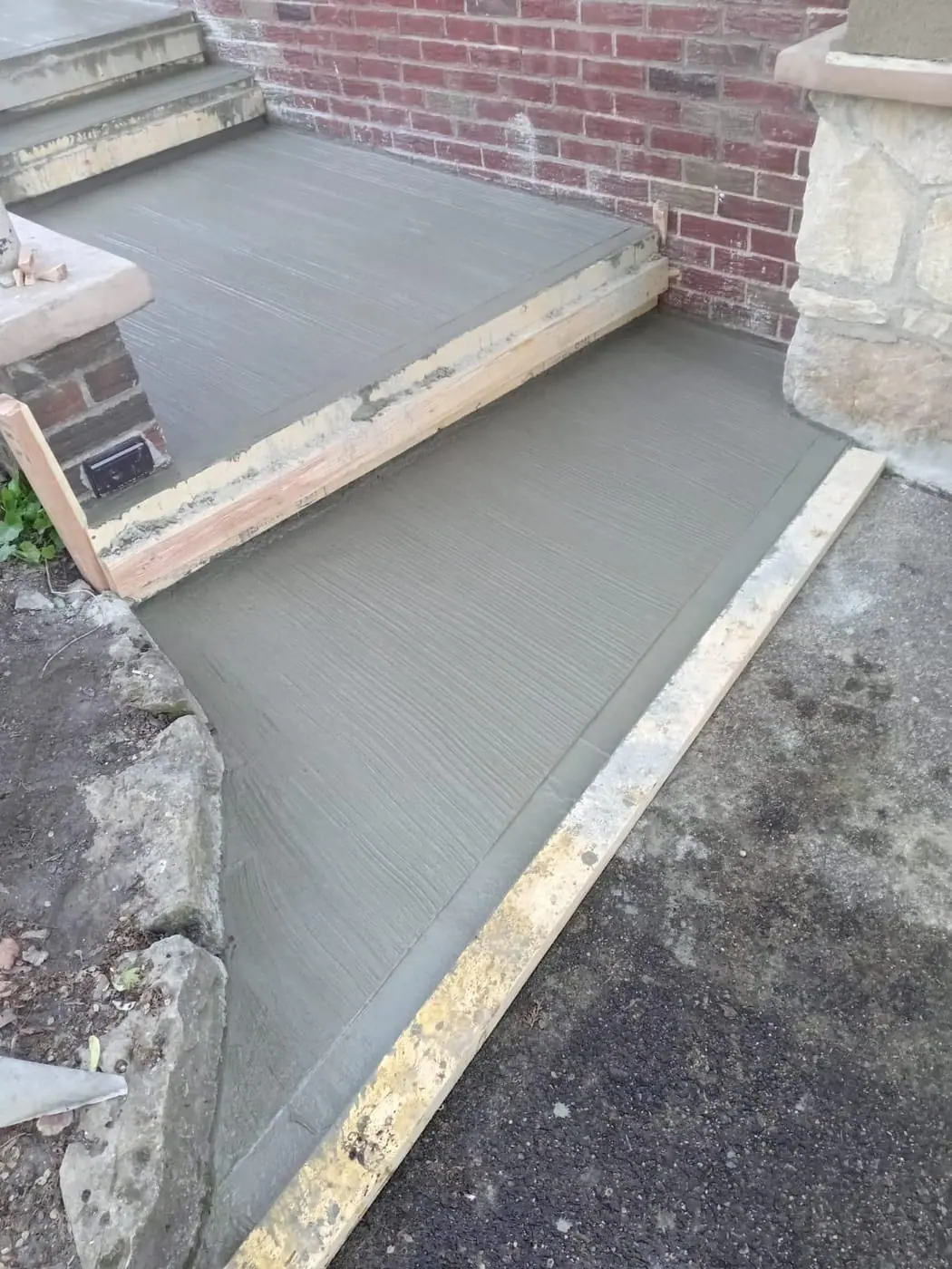 Freshly poured concrete steps formed alongside brick and stone
