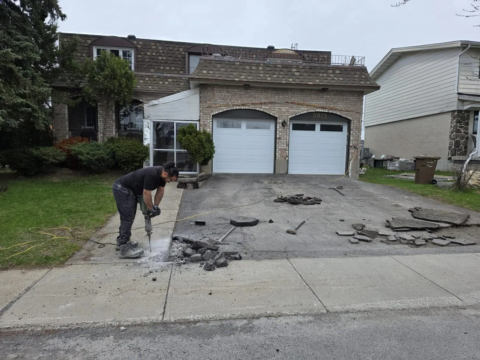 Existing driveway being broken out with a jackhammer in front of a house