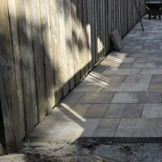 Detail of interlocking pavers meeting the stone-clad wall