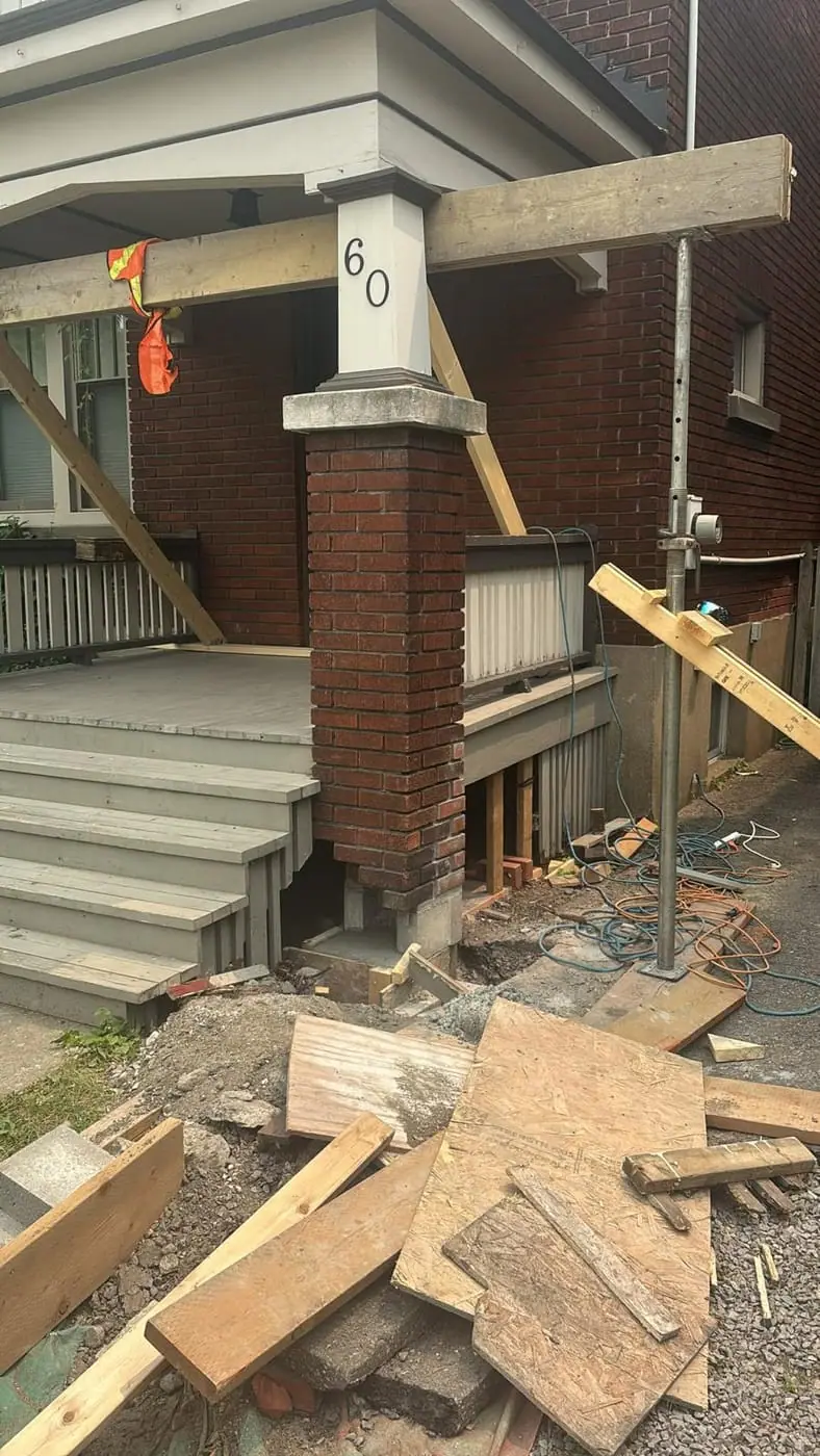 Porch with a brick column held up by temporary timber shoring during demolition
