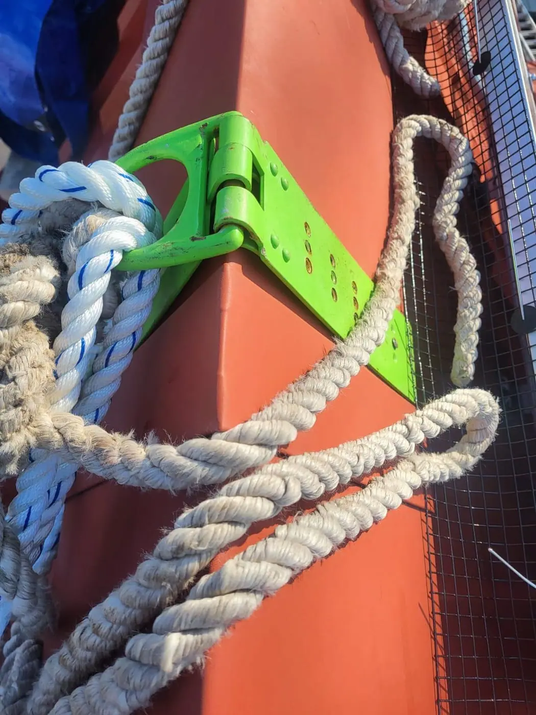 Roof anchor with rope in use on a red metal roof