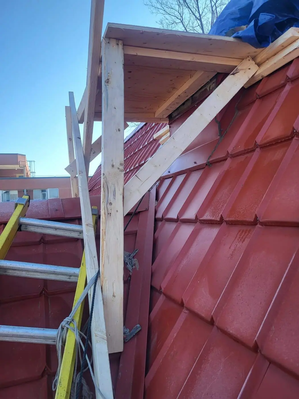 Novastone Contracting timber work platform braced against a metal roof with a ladder