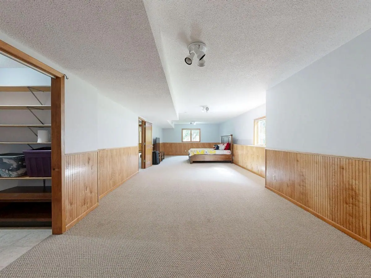 Finished basement hallway with carpet, panelled walls and a ceiling with recessed lighting