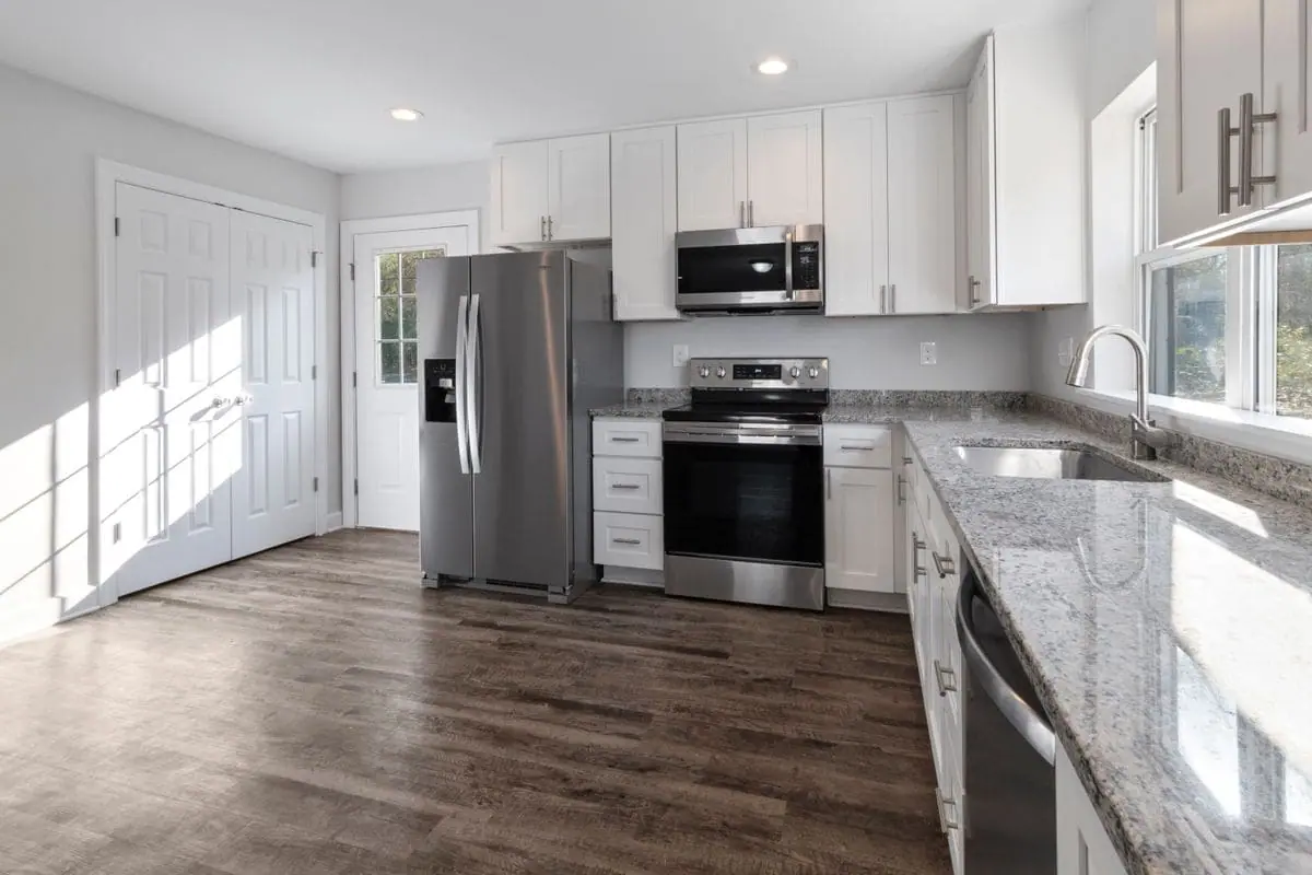 Bright kitchen with white cabinets, stainless appliances and laminate flooring