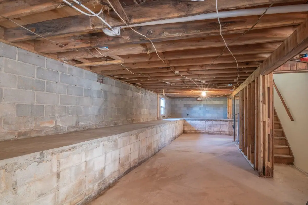 Unfinished basement with exposed joists, block walls and a concrete floor