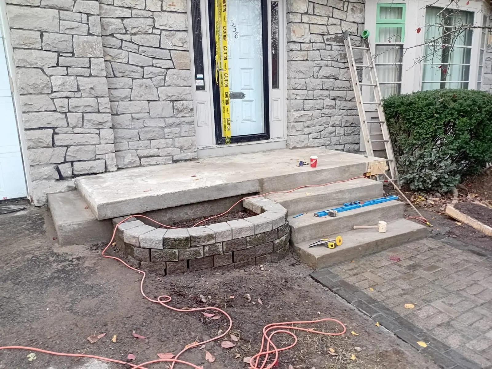 Front entry under construction with new concrete stoop and curved paver feature